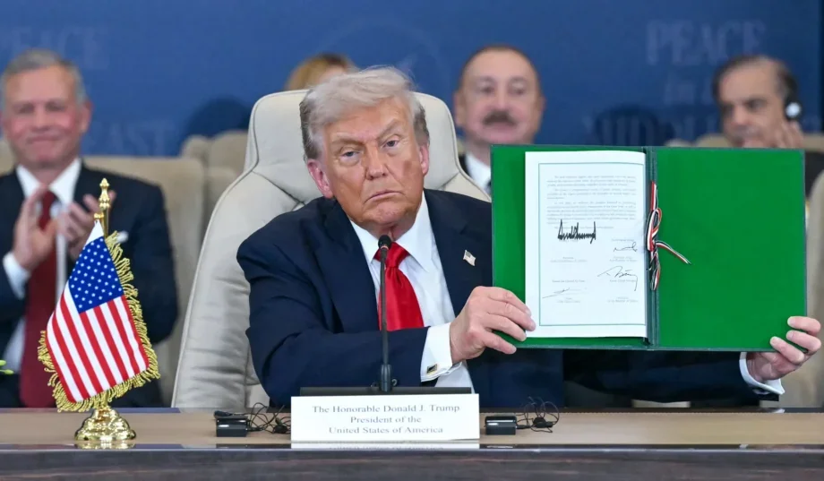 Дональд Трамп держит устав «Рады мира» на пресс-конференции с флагами США