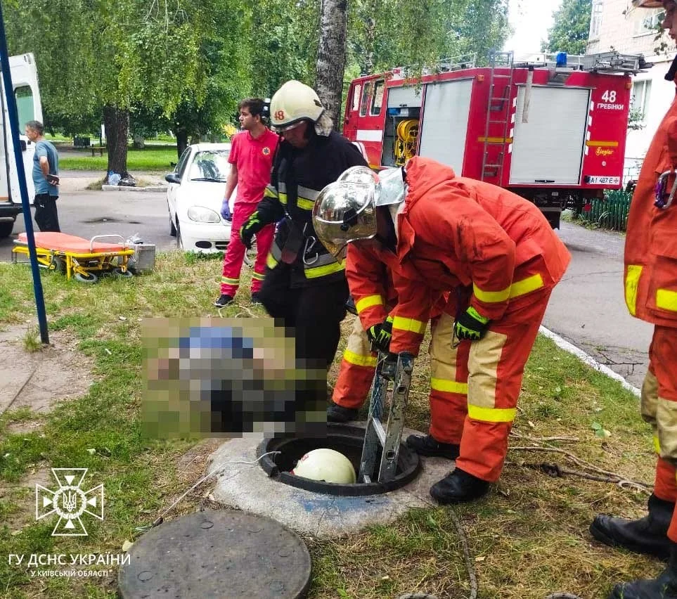 Слюсарі аварійної бригади у Києві витягають тіло з каналізаційного люка