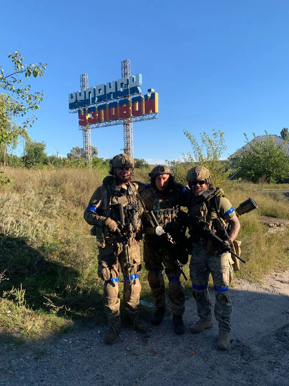 Трое бойцов ЗСУ возле знака «Купянск-Узловой» в Харьковской области.