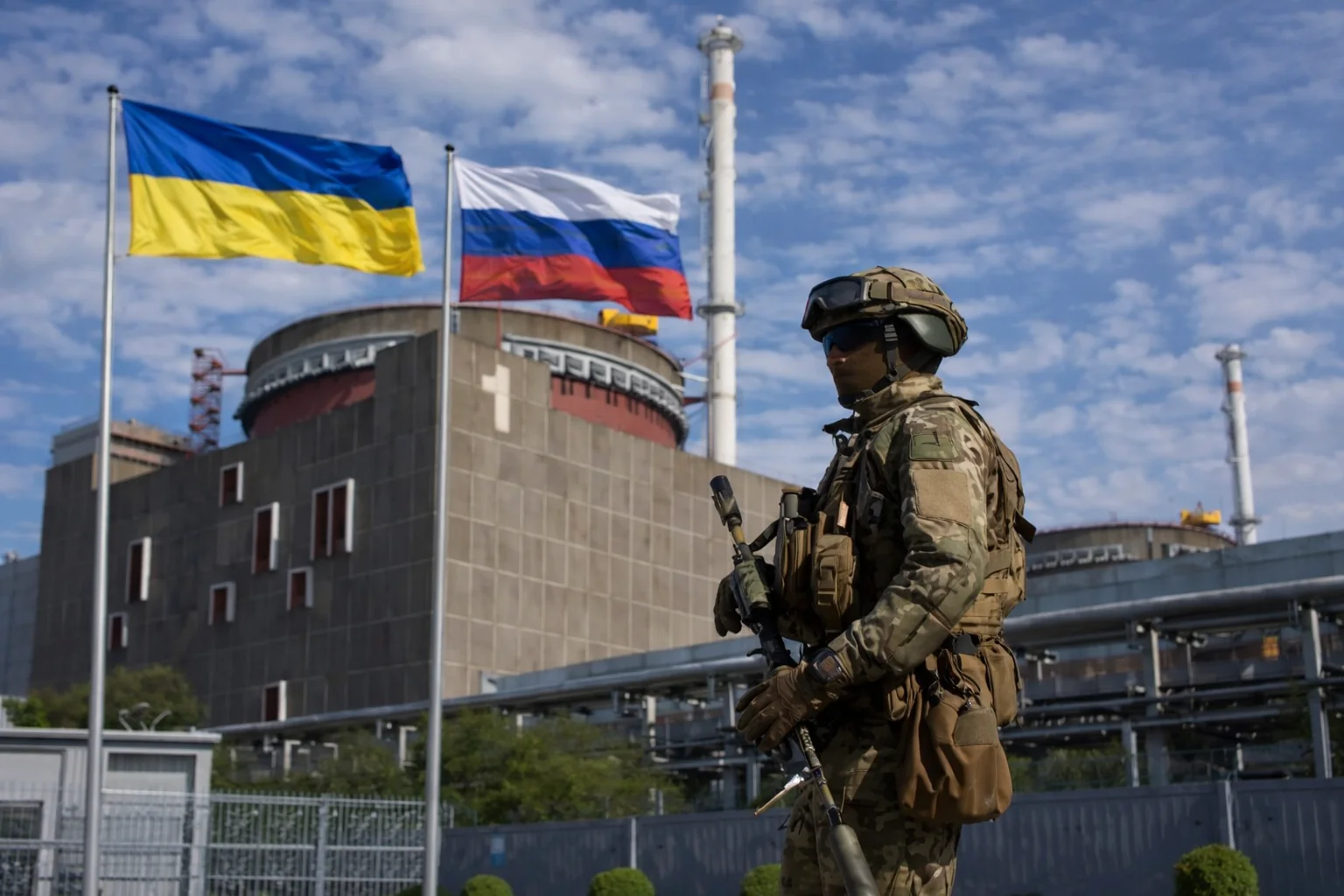 Российский военнослужащий охраняет Запорожскую АЭС под флагами Украины и России