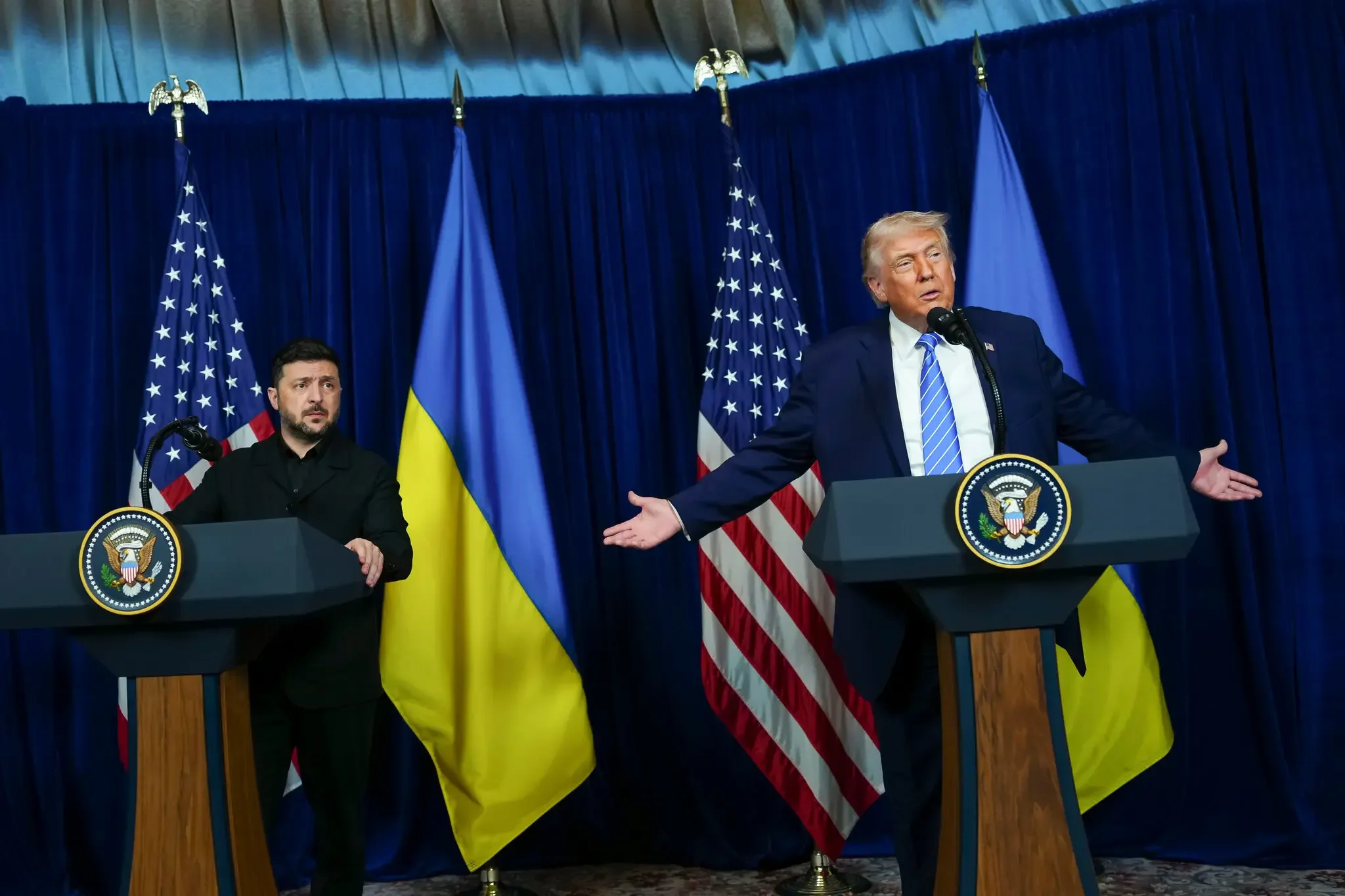 Дональд Трамп і Володимир Зеленський за трибунами з прапорами США та України під час переговорів