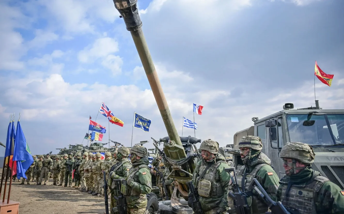 Європейські сили НАТО з прапорами Франції, Іспанії, Латвії біля гаубиці без США