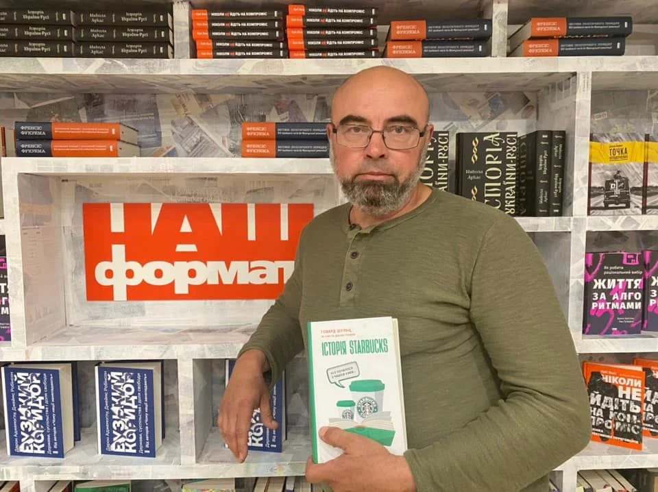 Владислав Кириченко тримає книгу «Китай» серед полиць видавництва «Наш Формат»