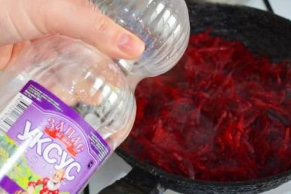 Оцет ллють на нарізаний буряк у сковороді для засмажки червоного борщу