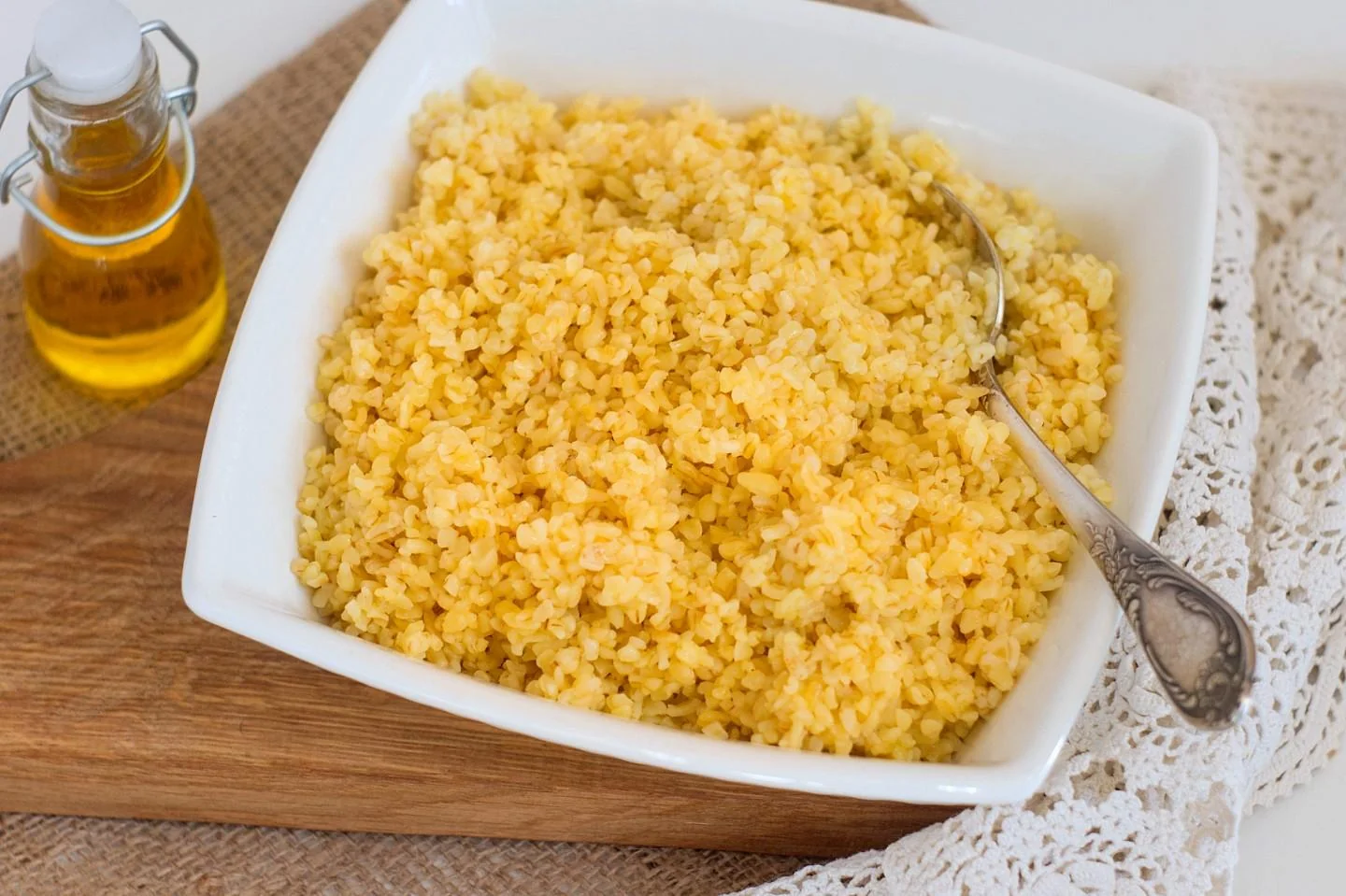 Кускус, приготовленный на кипятке без плиты, в белой миске с ложкой и маслом