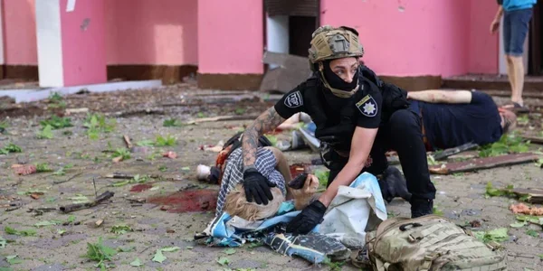 Рятувальник у формі допомагає пораненому серед руйнувань Слобідського району Харкова після ударів КАБами
