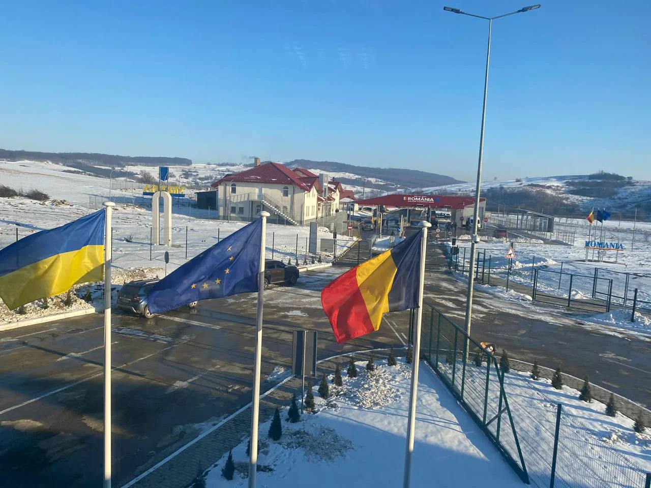 Пограничный пункт Украина-Румыния зимой с флагами Украины, ЕС и Румынии на снегу
