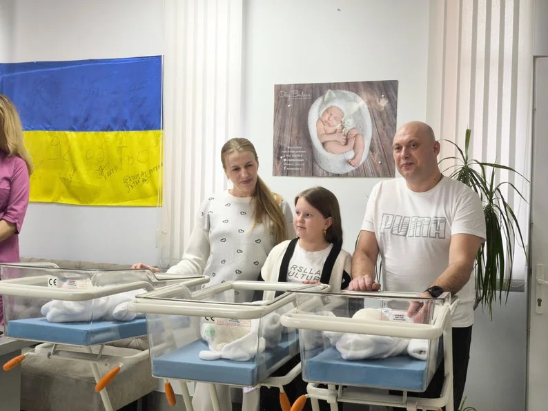 Ірина та Ілля Звонецькі з дочкою біля трійні новонароджених дівчаток у пологовому