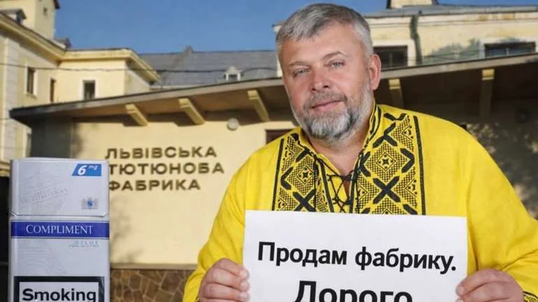 Чоловік з плакатом «Продаж фабрики. Допоможи» перед Винниківською тютюновою фабрикою