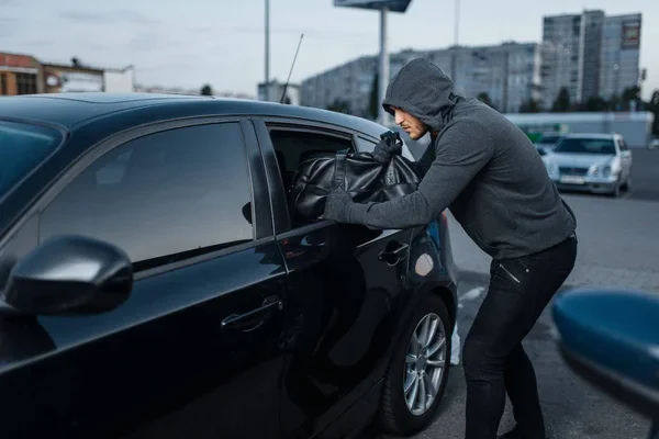 Зловмисник на київській автомийці витягує сумку з багажника клієнтського авто