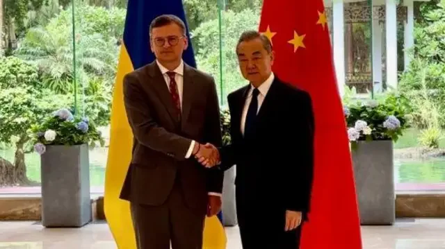Министр Ван И пожимает руку украинскому дипломату перед флагами Китая и Украины