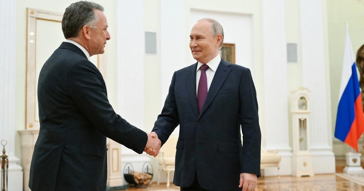 Володимир Путін тисне руку Олександру Лукашенку на тлі прапорів РФ і Білорусі