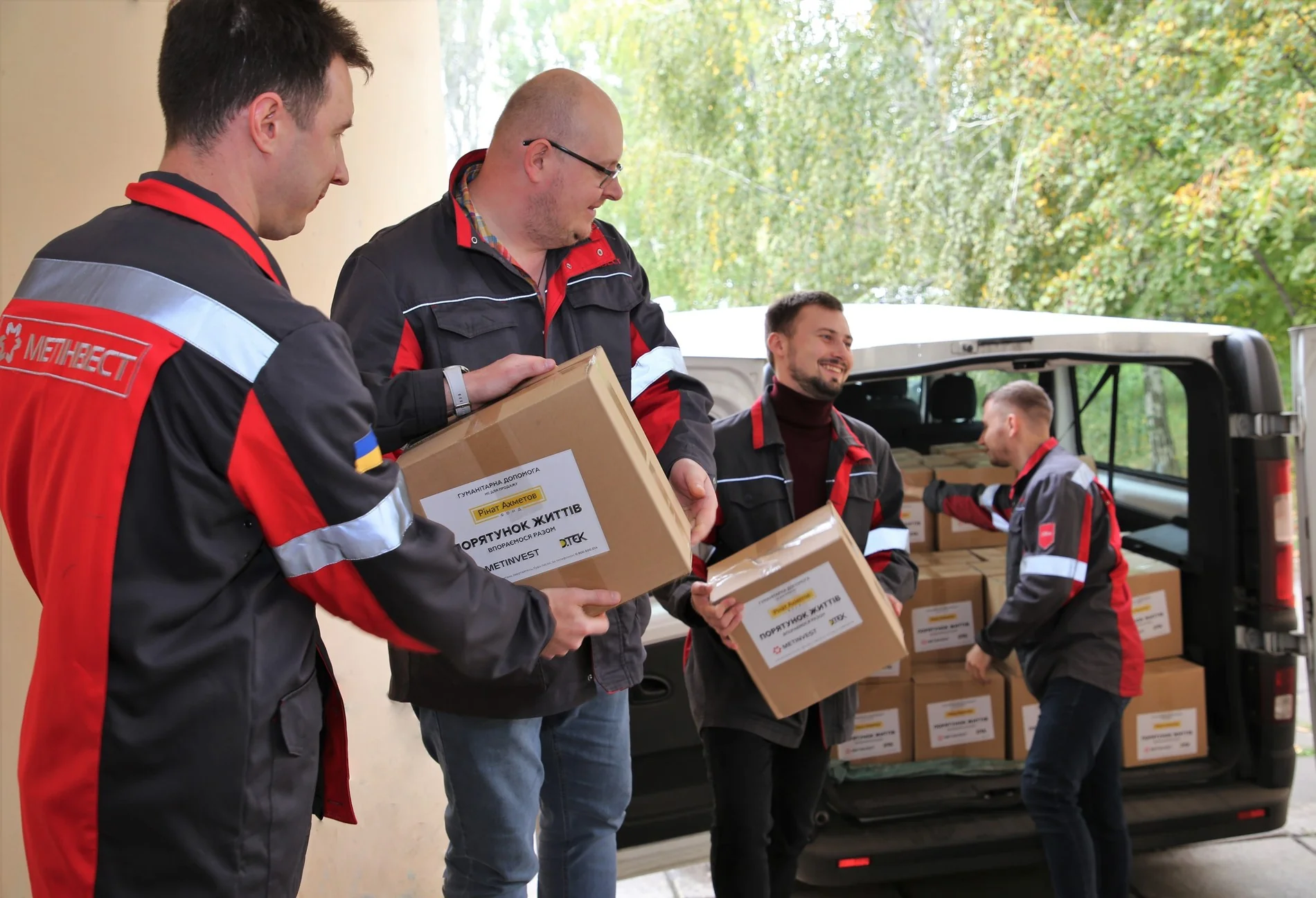 Співробітники Метінвесту розвантажують коробки гуманітарної допомоги з фургона