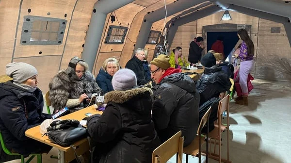 Пункт незламності Метінвесту для киян взимку: люди в теплих куртках за столами