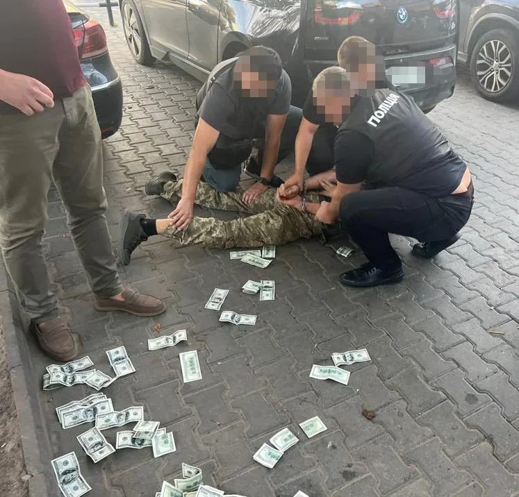 Офіцери ТЦК затримають побитого мобілізованого серед розкиданих доларів на вулиці