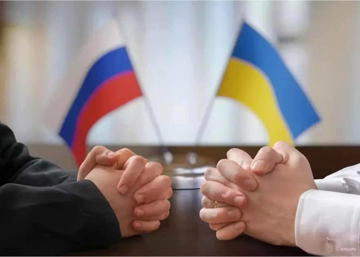 Руки України та РФ у жесті компромісу щодо зони на Донбасі з прапорами