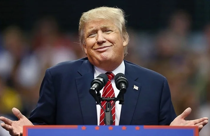 Дональд Трамп жестикулирует за трибуной, намекая на третий президентский срок