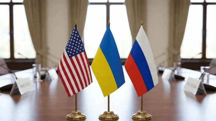 Прапори України, США та РФ на столі тристоронніх переговорів