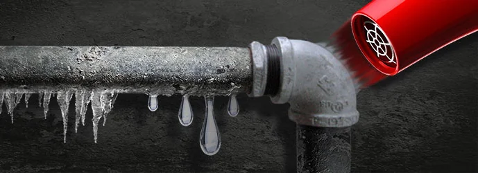 Замерзлі водопровідні труби з льодом, на які дує гарячим повітрям червоний фен від морозу.