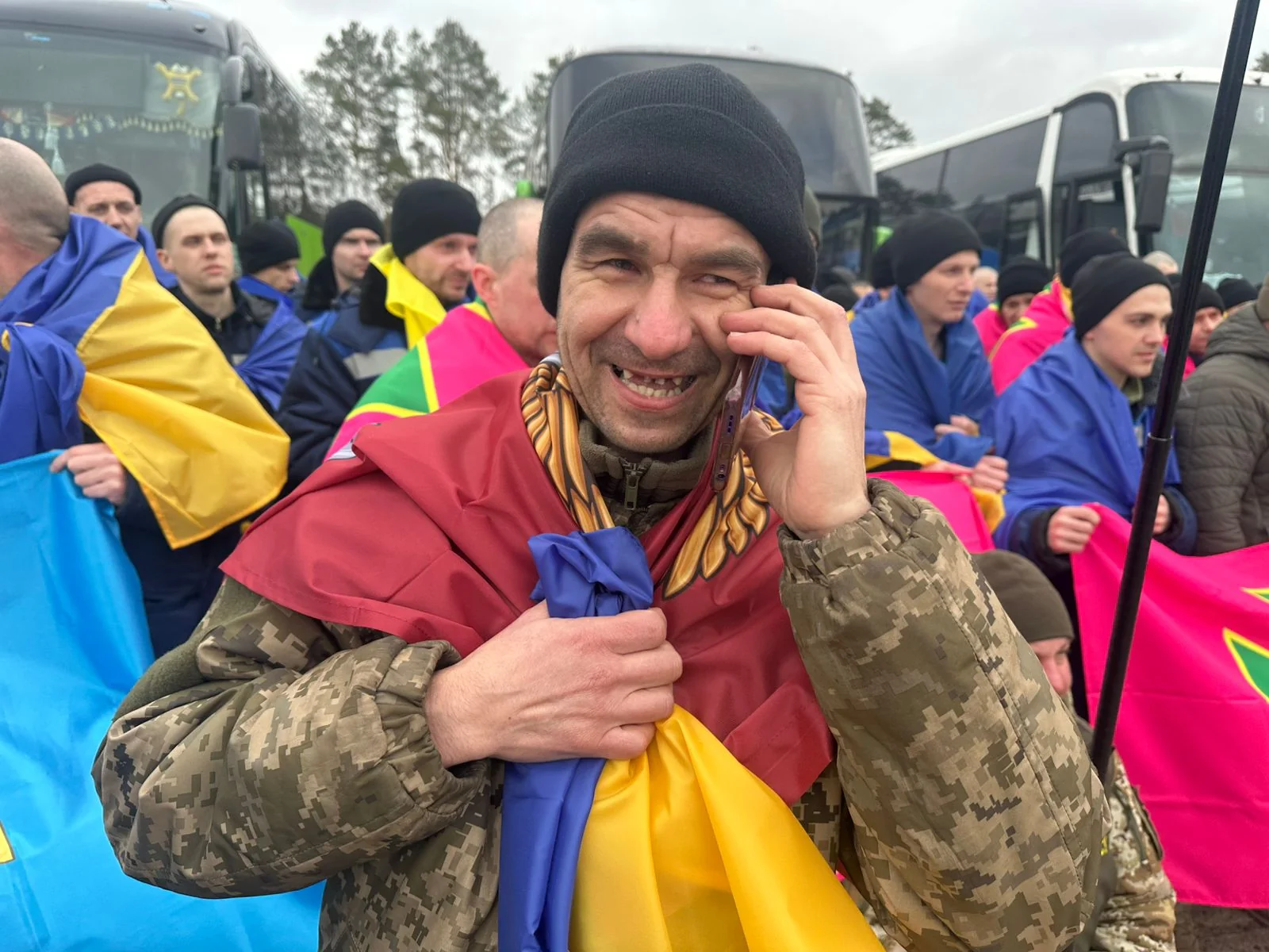 Радісні українські полонені з прапорами біля автобусів після повернення додому