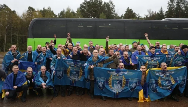 Звільнені українські захисники після другого етапу обміну з прапорами біля автобуса