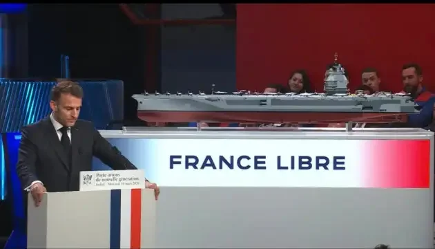 Емманюель Макрон презентує модель авіаносця «Вільна Франція» (France Libre) на трибуні.