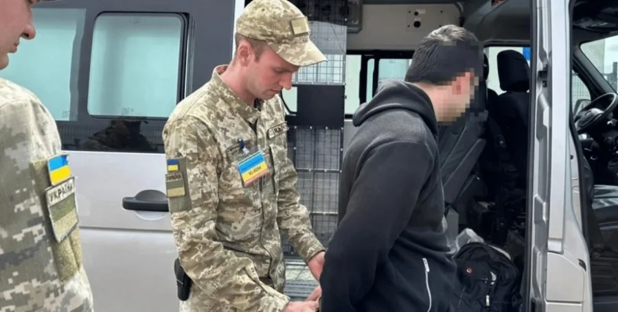 Сотрудники ТЦК затаскивают забронированного мужчину в микроавтобус во время мобилизации