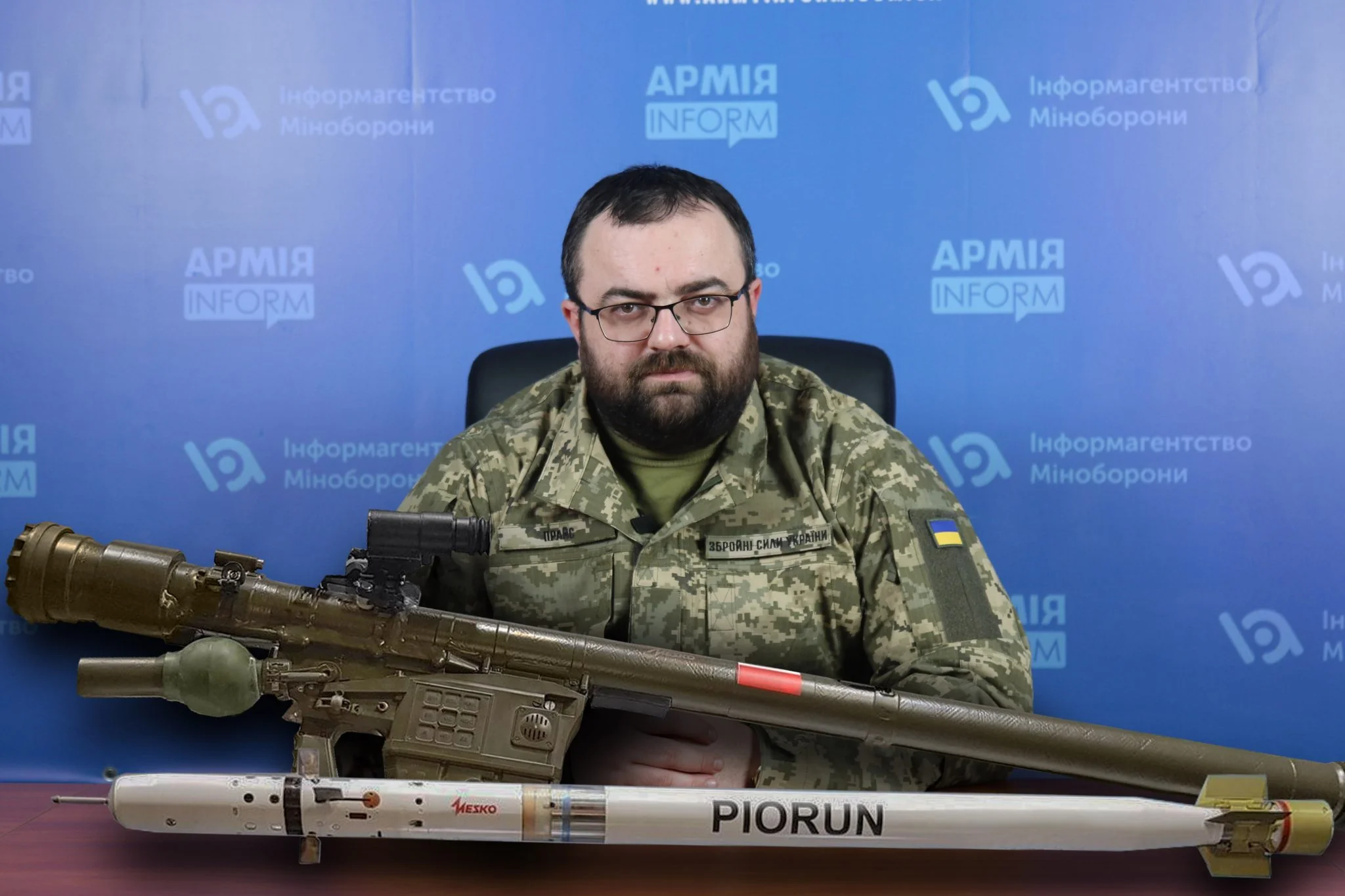Командир 1-го ОШП «Перун» (Дмитро Філатов) тримає гранатомет «ПІОРУН» на фоні банерів «АРМІЯ»