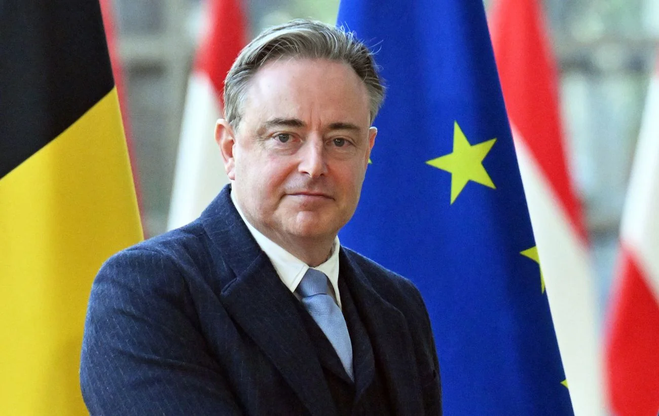 Премєр-міністр Бельгії Барт Де Вевер на тлі прапорів Бельгії та ЄС