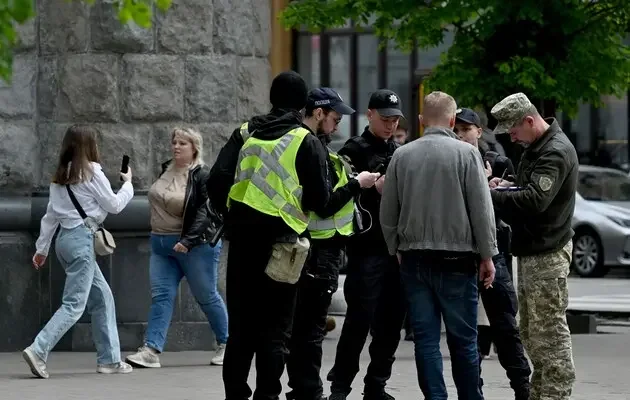 Представники ТЦК у жовтих жилетах і поліція перевіряють людей на вулиці під час мобілізації