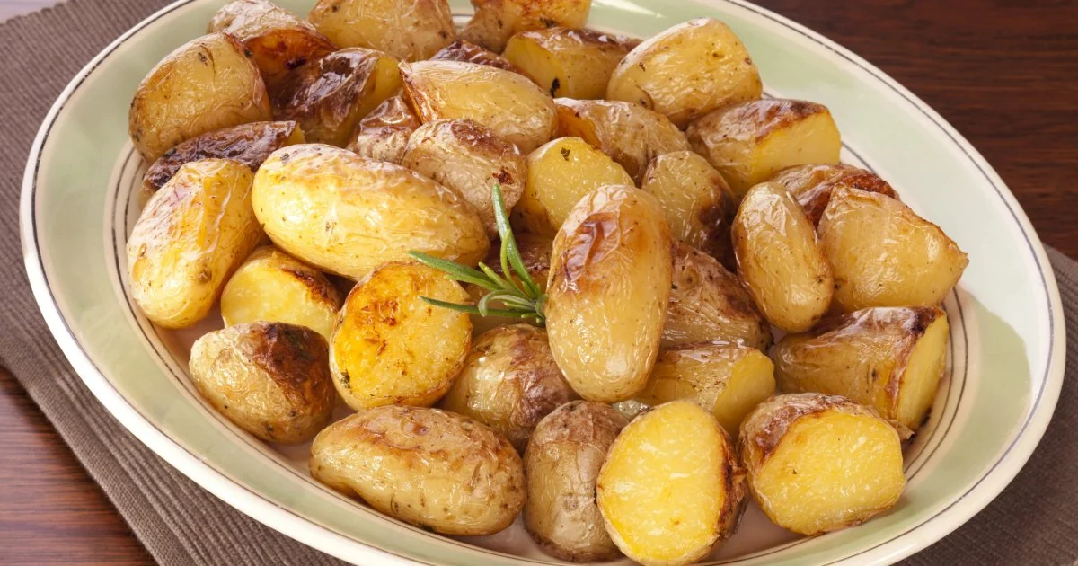 Варена картопля з гілочками розмарину на зеленій тарілці