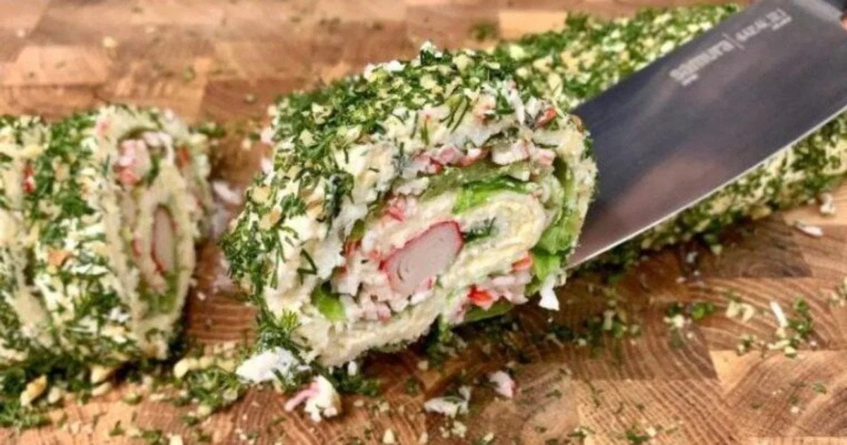 Рулет без лаваша с крабовыми палочками и плавлёным сыром, разрезанный на доске