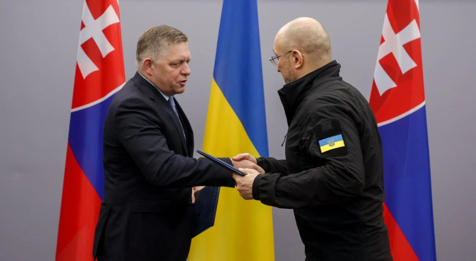 Словацький міністр Річард Такач тисне руку українському колезі перед прапорами