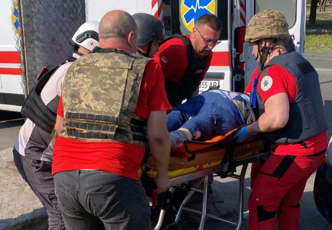Рятувальники несуть пораненого в Шостці на ношах до швидкої після збиття дронів.