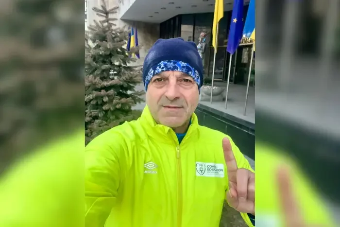 Нардеп Григорій Мазурашу в спортивній куртці показує великий палець біля прапорів у Києві
