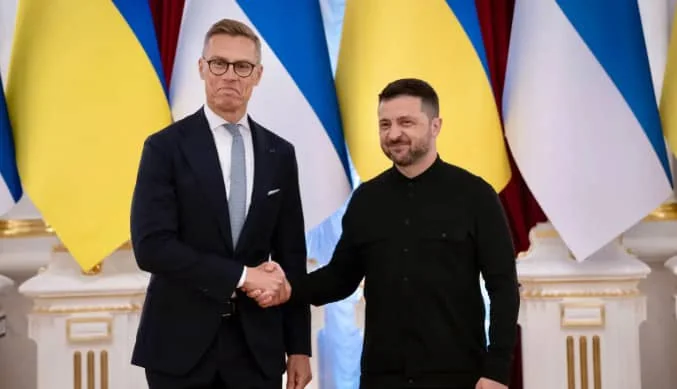 Рукостискання представників України та Фінляндії під національними прапорами