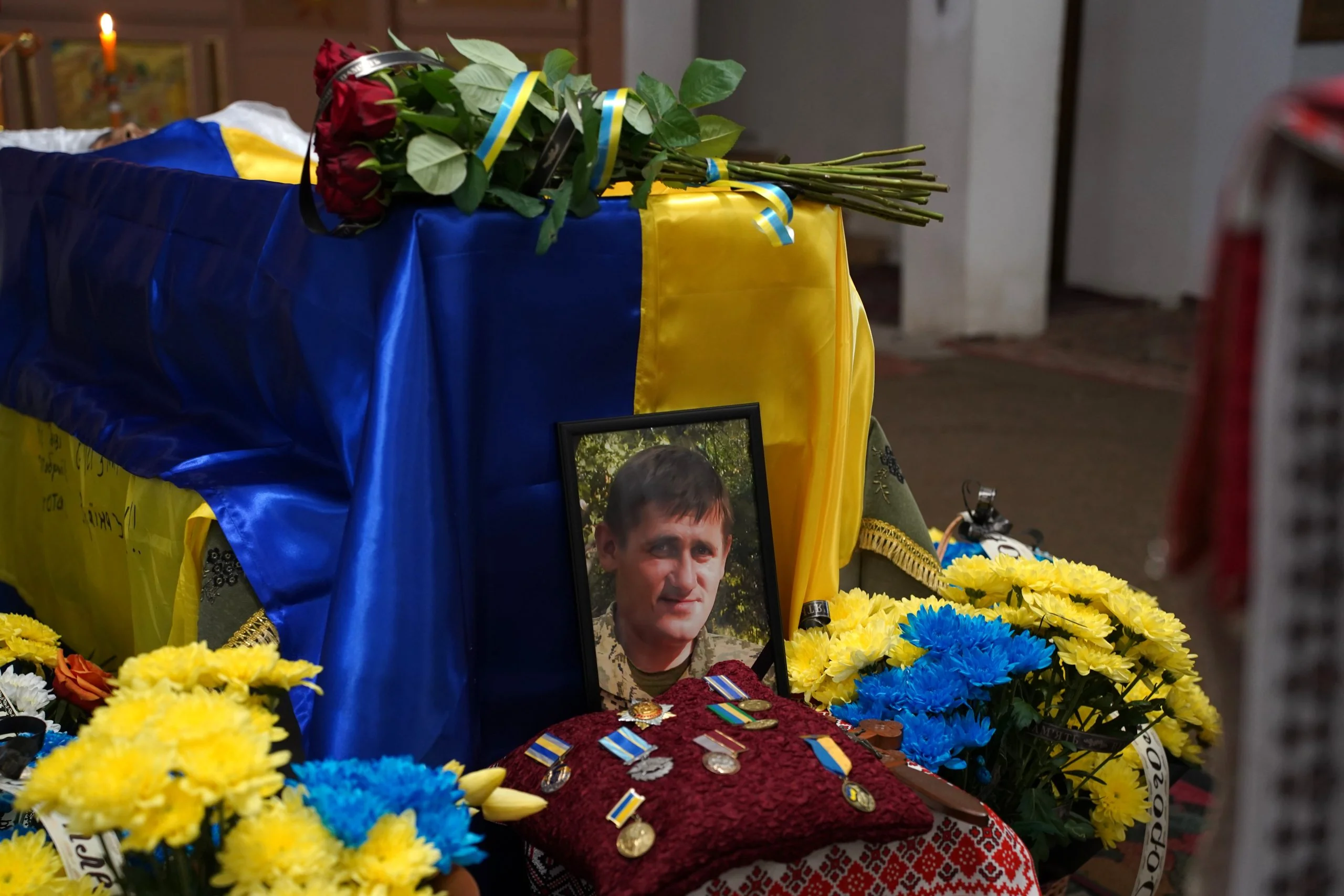 Могила Юрия Фелипенко с портретом героя, цветами и сине-желтыми лентами