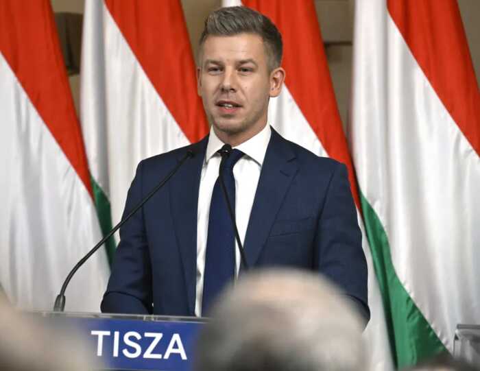 Петер Мадьяр виступає за трибуною партії Тиса на тлі прапорів Угорщини