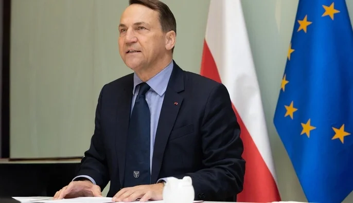 Міністр закордонних справ Польщі Радослав Сікорський на тлі прапорів Польщі та ЄС