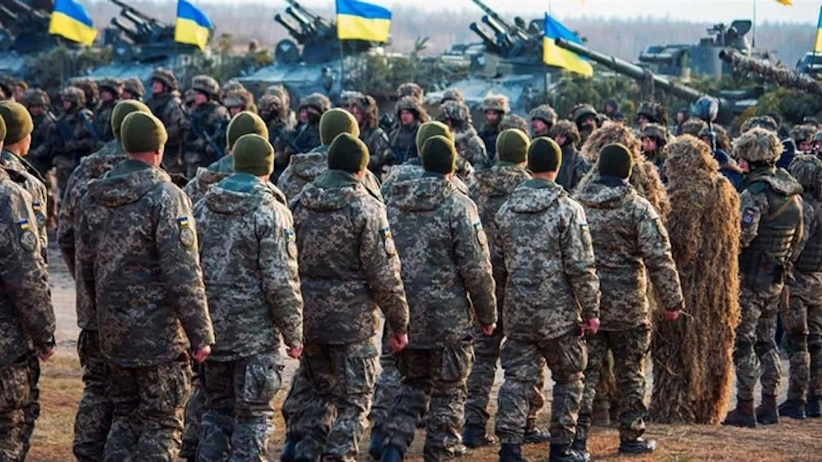Шеренга бійців ЗСУ в камуфляжі з прапорами та танками під час мобілізації