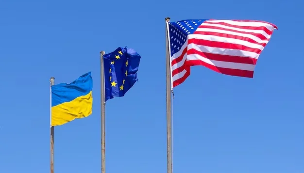 Прапори України, ЄС та США майорять на вітрі на блакитному небі