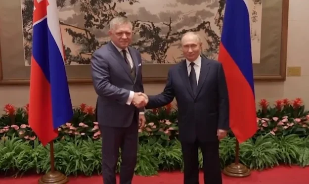 Роберт Фіцо та Володимир Путін потискають руки перед прапорами Словаччини і Росії