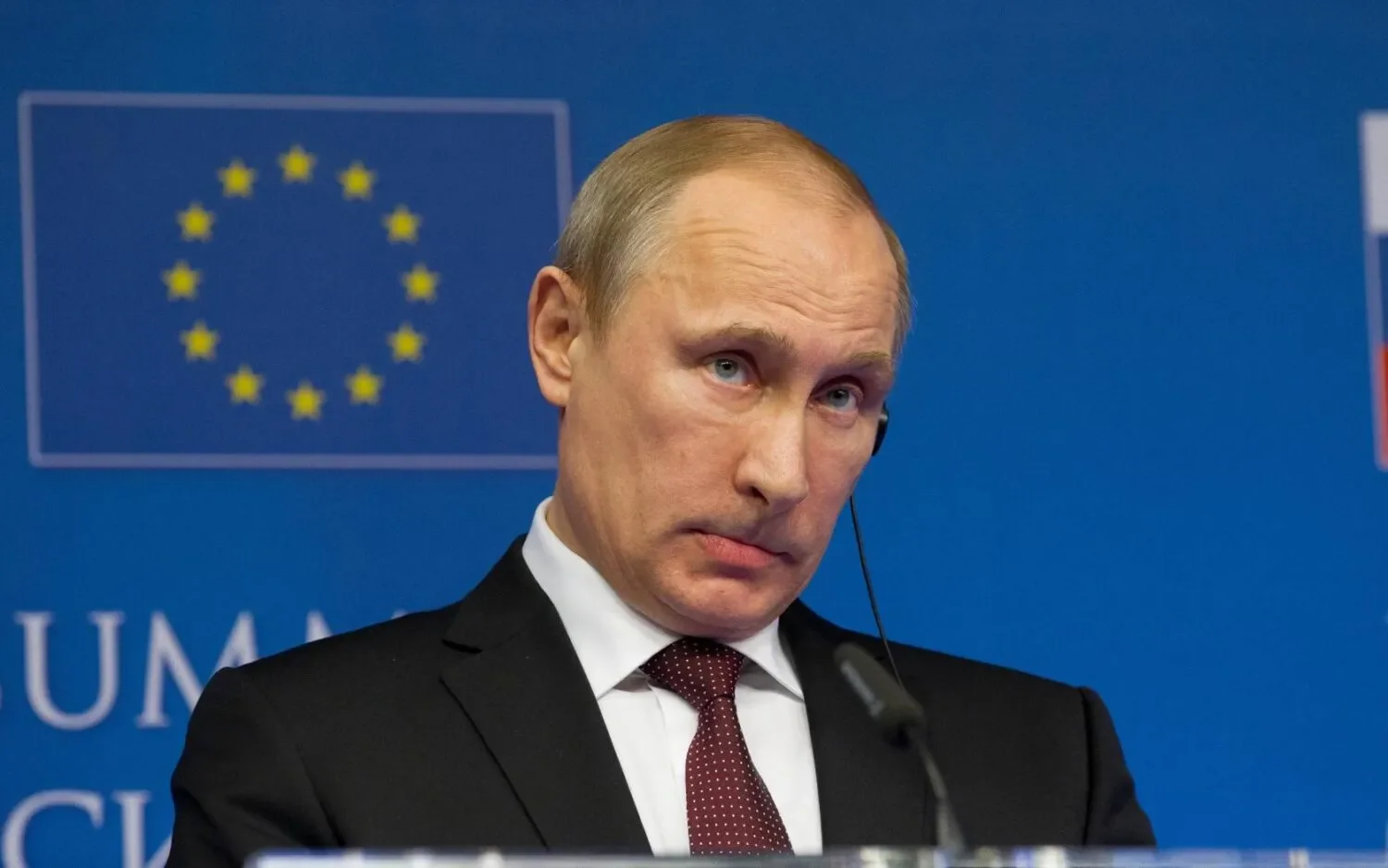 Владимир Путин за трибуной на фоне флагов ЕС и РФ, обеспокоенный рисками переворота и дронов