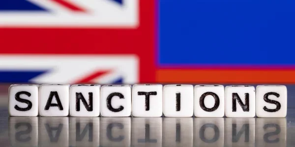 SANCTIONS кубиками на тлі прапорів Британії та Росії