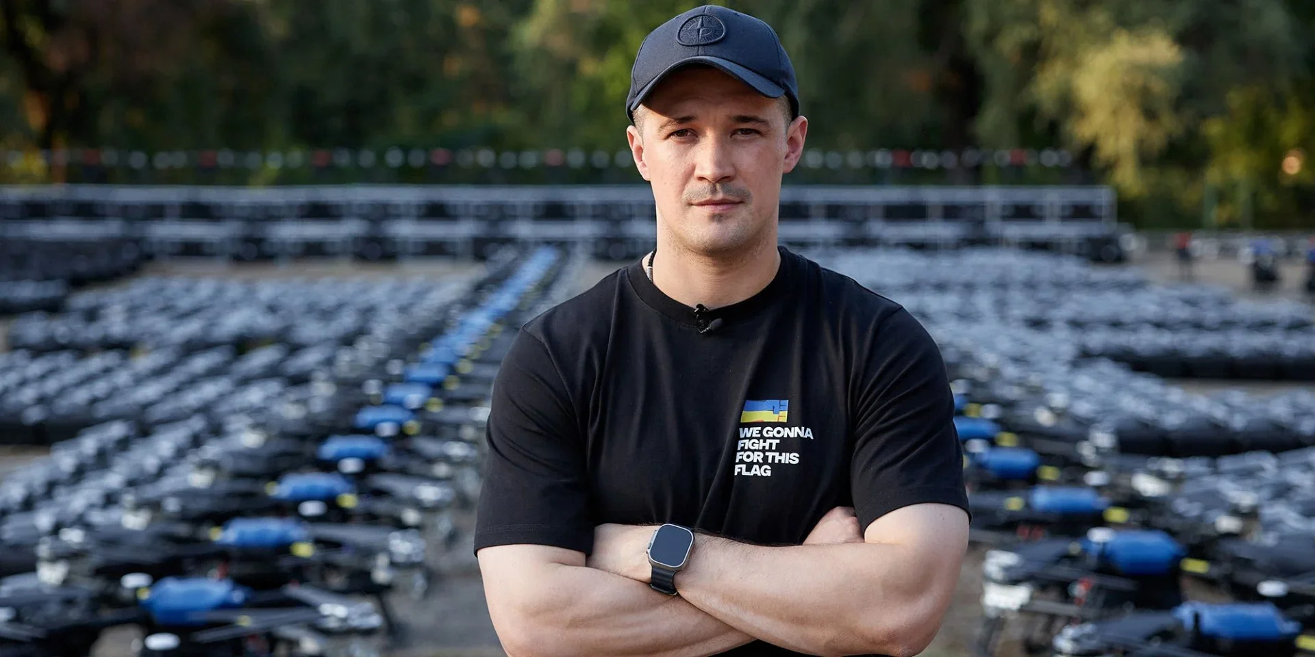 Михайло Драпатий на тлі вишикуваної військової техніки ЗСУ