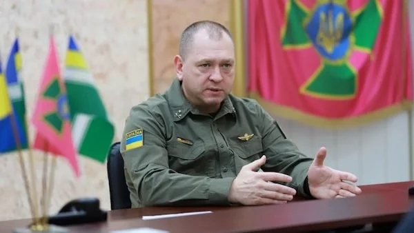 Топчиновник ДПСУ за робочим столом у службовому кабінеті з прапорами