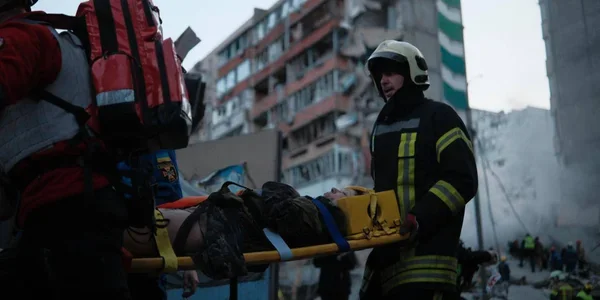 Рятувальники несуть постраждалого на ношах після ракетного удару по Києву