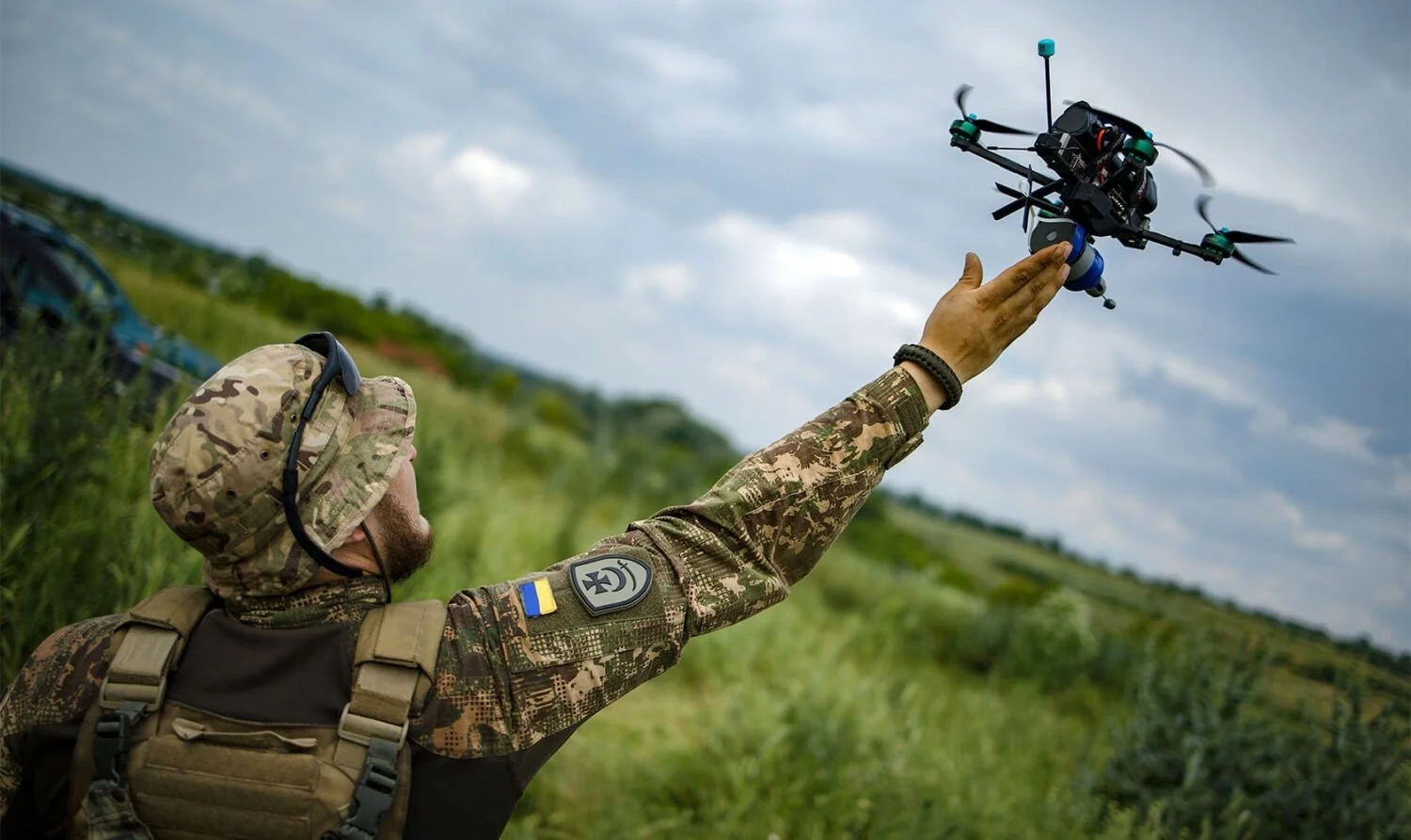 Український військовий запускає дрон на тлі поля під час війни майбутнього
