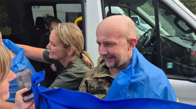 Звільнений журналіст Єсипенко посміхається загорнутий у прапор України