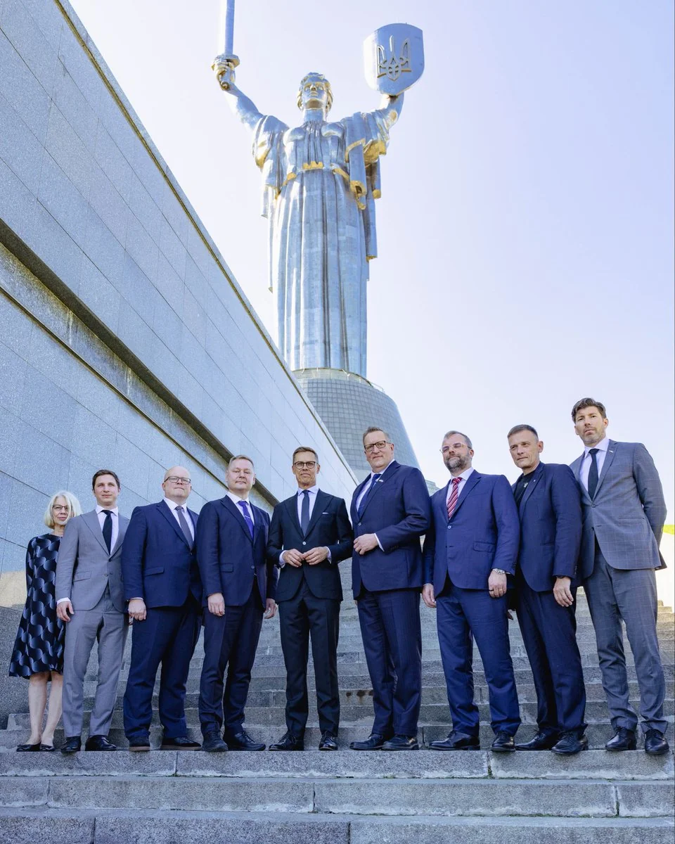 Група людей у костюмах стоїть на сходах перед Монументом Батьківщини-Матері в Києві